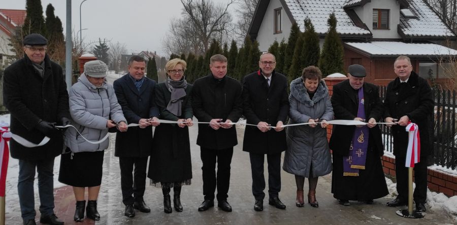 Otwarcie kolejnych gminnych dróg przebudowanych dzięki Rządowemu Funduszowi Rozwoju Dróg. Osoby przecinające wstęgę.